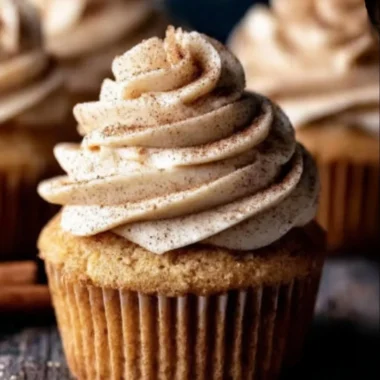 Delicious apple cider cupcakes with spiced buttercream frosting on a rustic table.