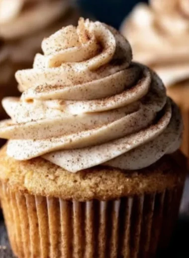 Delicious apple cider cupcakes with spiced buttercream frosting on a rustic table.