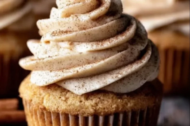 Delicious apple cider cupcakes with spiced buttercream frosting on a rustic table.