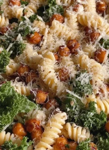 Kale Caesar Pasta Salad in a bowl topped with croutons and Parmesan cheese