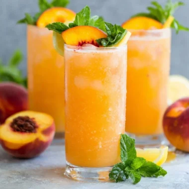 Refreshing peach lemonade in a glass with a peach slice and lemon wedge
