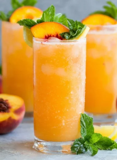 Refreshing peach lemonade in a glass with a peach slice and lemon wedge
