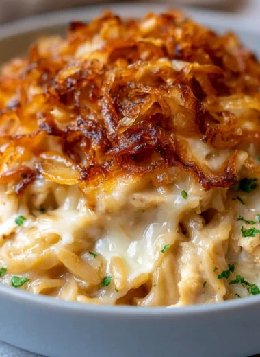 French onion chicken orzo casserole baked in a dish with melted cheese on top.