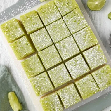Delicious lime bars on a white plate garnished with lime slices