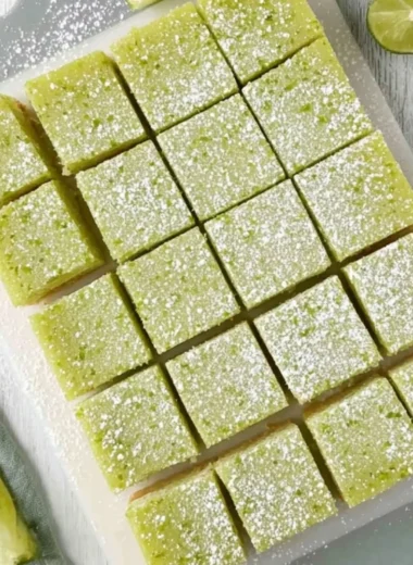 Delicious lime bars on a white plate garnished with lime slices