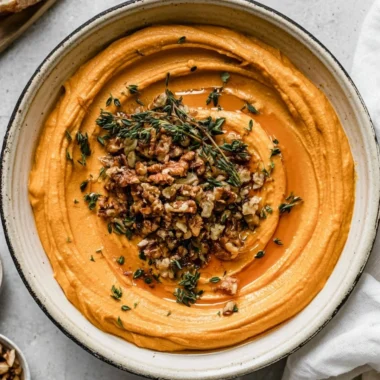 Delicious pumpkin whipped feta spread served in a bowl, garnished with herbs.
