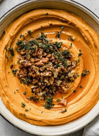Delicious pumpkin whipped feta spread served in a bowl, garnished with herbs.