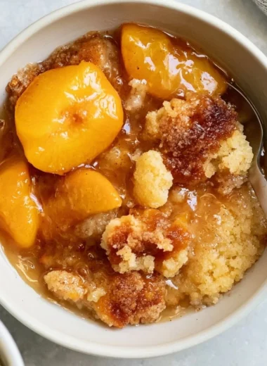 Homemade Southern peach cobbler topped with fresh peaches and a golden crust