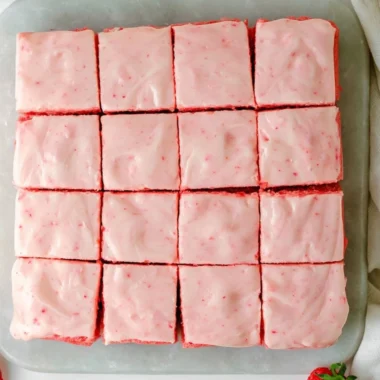 Delicious strawberry brownies topped with creamy frosting on a plate
