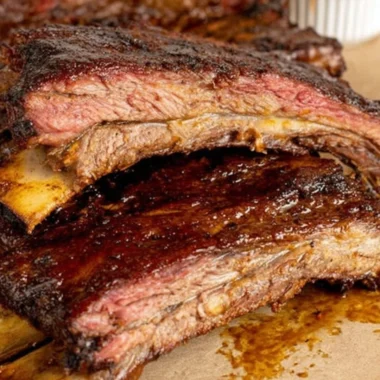 Tender smoky beef ribs on a grill, showcasing rich flavors and perfect seasoning.