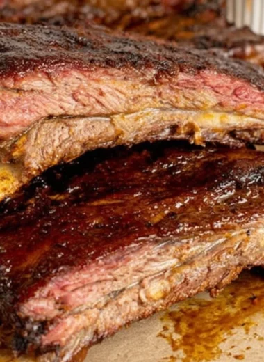 Tender smoky beef ribs on a grill, showcasing rich flavors and perfect seasoning.