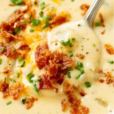 Delicious bowl of creamy baked potato soup garnished with chives and cheese.