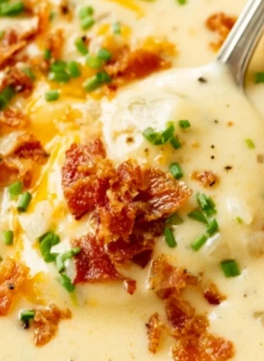 Delicious bowl of creamy baked potato soup garnished with chives and cheese.