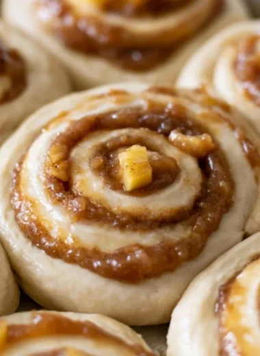 Freshly baked caramel apple cinnamon rolls drizzled with caramel sauce.