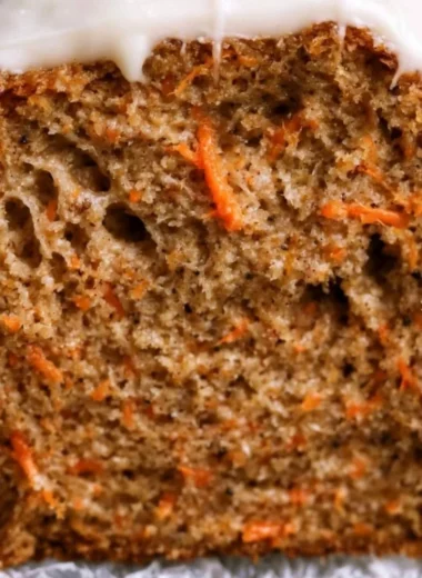 Deliciously moist carrot cake loaf with cream cheese frosting on a rustic table.