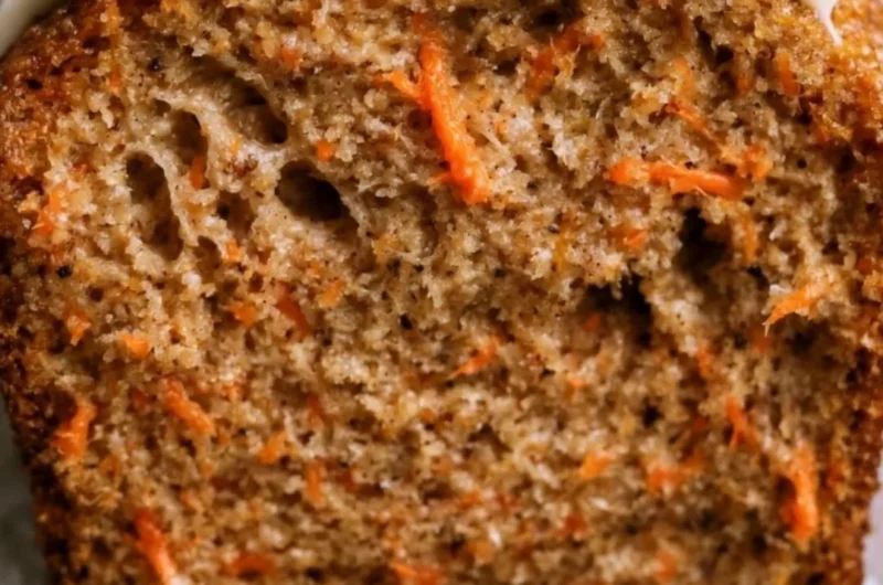Deliciously moist carrot cake loaf with cream cheese frosting on a rustic table.