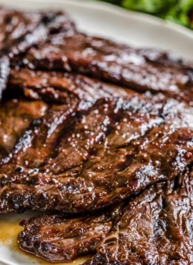 Citrus marinated grilled flank steak served on a plate with herbs.