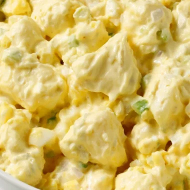 Bowl of creamy potato salad with fresh herbs and vegetables