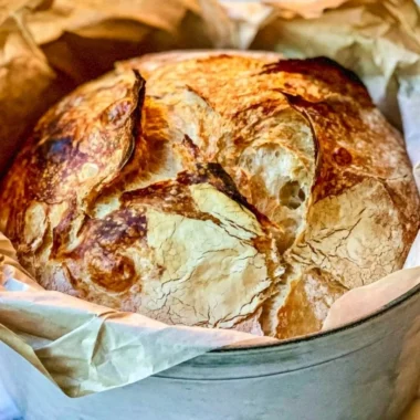 Loaf of easy Dutch Oven bread on a wooden board, fresh out of the oven