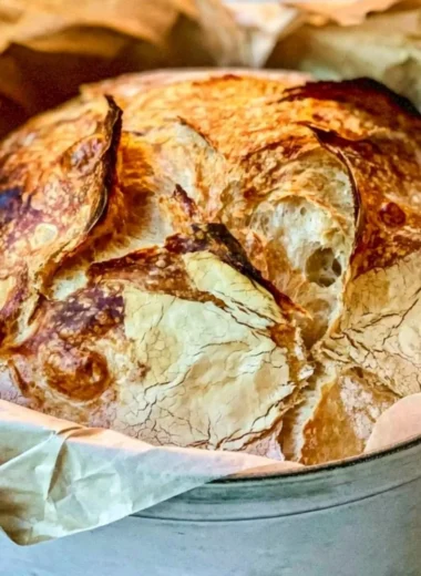 Loaf of easy Dutch Oven bread on a wooden board, fresh out of the oven