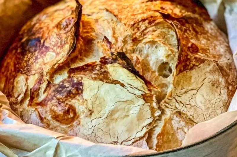 Loaf of easy Dutch Oven bread on a wooden board, fresh out of the oven