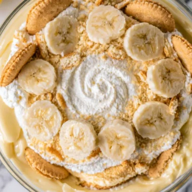 A bowl of homemade banana pudding topped with whipped cream and banana slices.