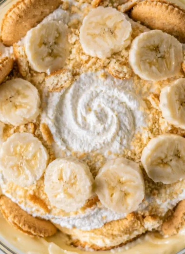 A bowl of homemade banana pudding topped with whipped cream and banana slices.