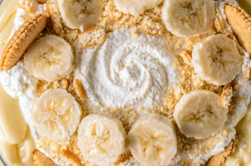 A bowl of homemade banana pudding topped with whipped cream and banana slices.