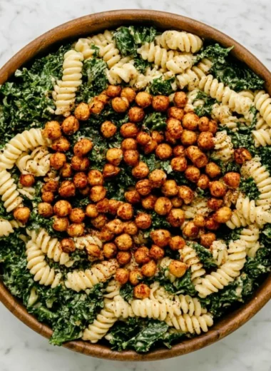 A colorful Kale Caesar Pasta Salad topped with creamy dressing and croutons