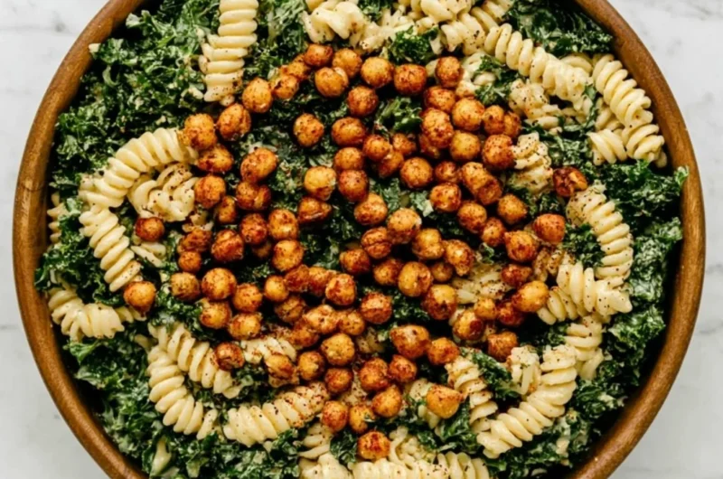 A colorful Kale Caesar Pasta Salad topped with creamy dressing and croutons