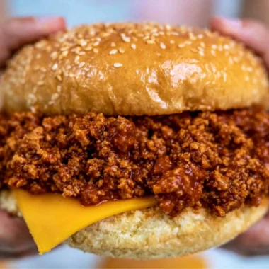 Bowl of slow cooker sloppy joes served with buns and garnished with parsley