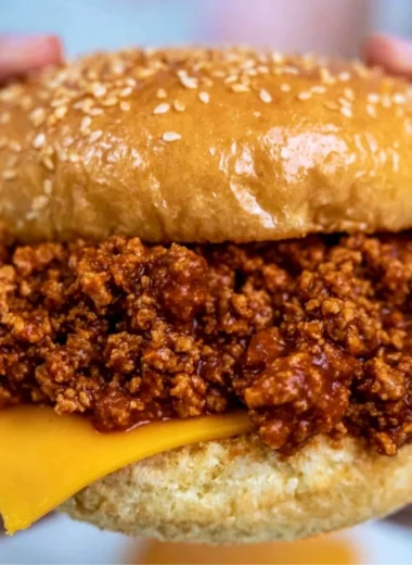 Bowl of slow cooker sloppy joes served with buns and garnished with parsley