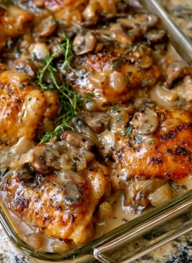 Baked chicken thighs topped with mushroom sauce in a glass dish